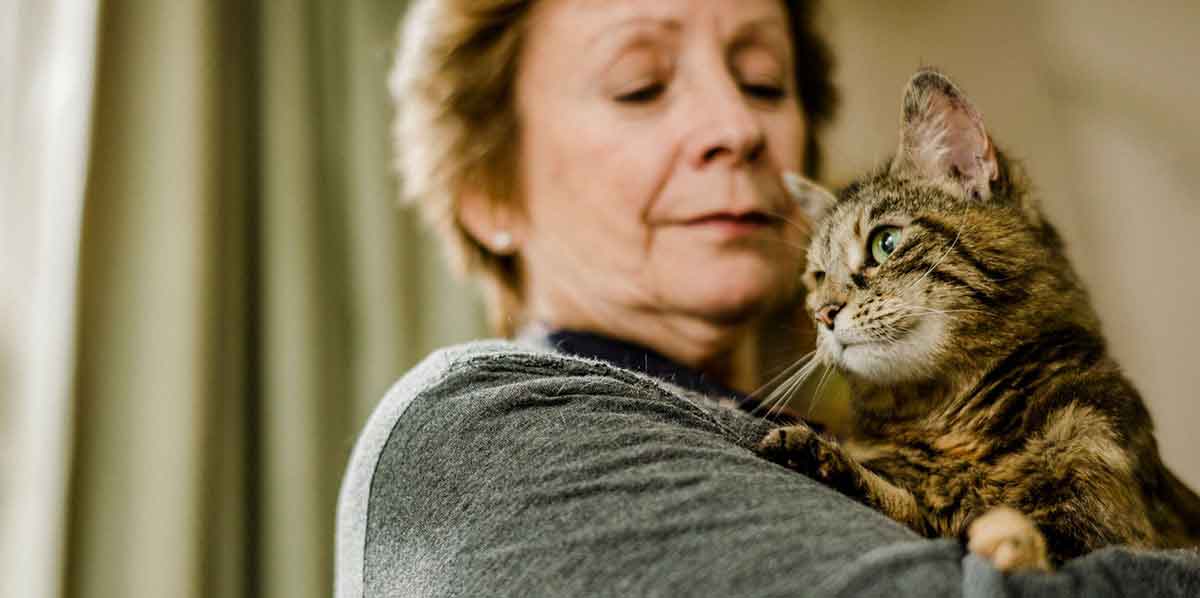 Older woman holding tabby cat