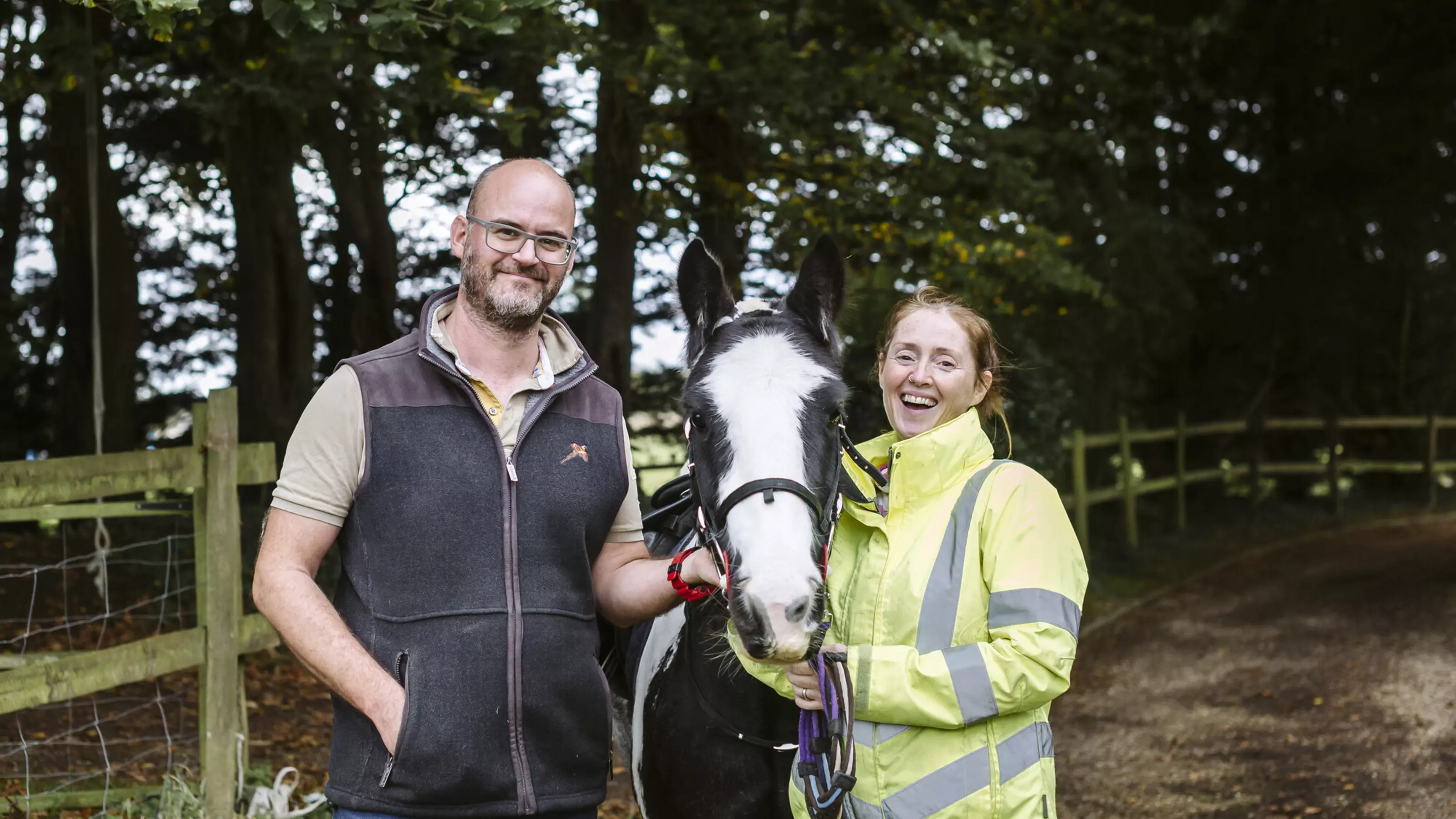 Micky, the black and white horse, with new owners Abi and James standing either side of him