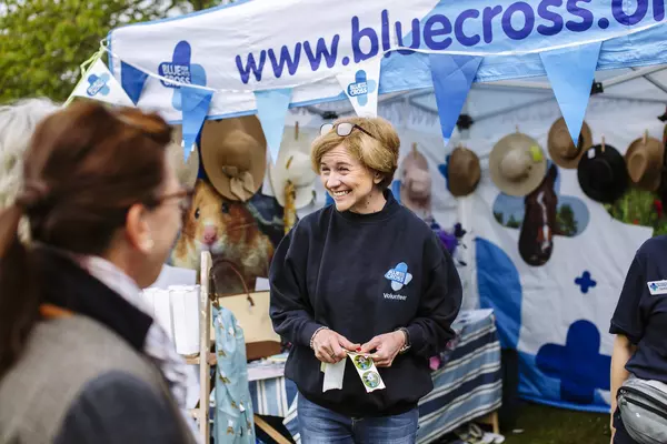 Photograph of woman giving out Blue Cross stickers at Kimpton dog show