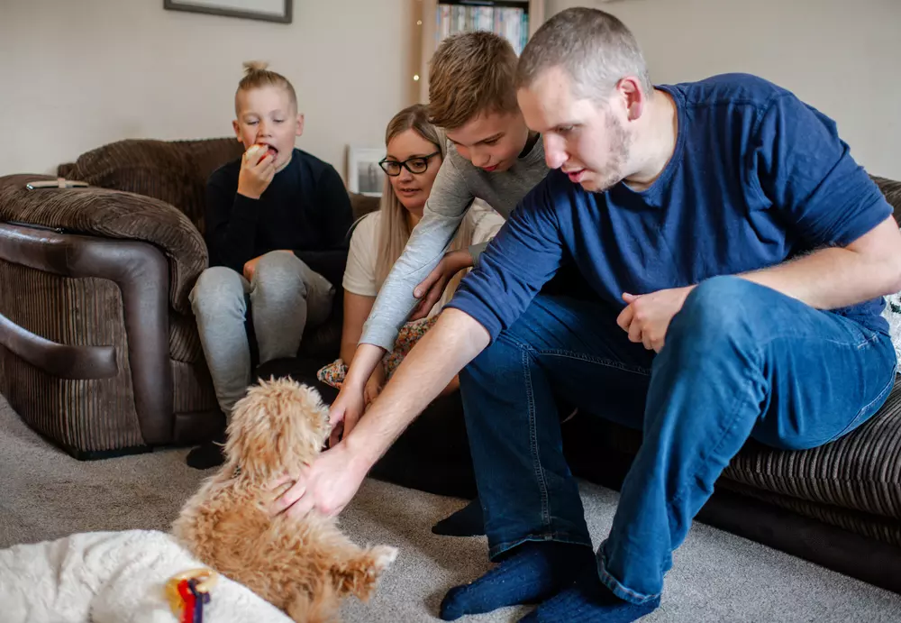 A family make a fuss of their poochon puppy Nancy
