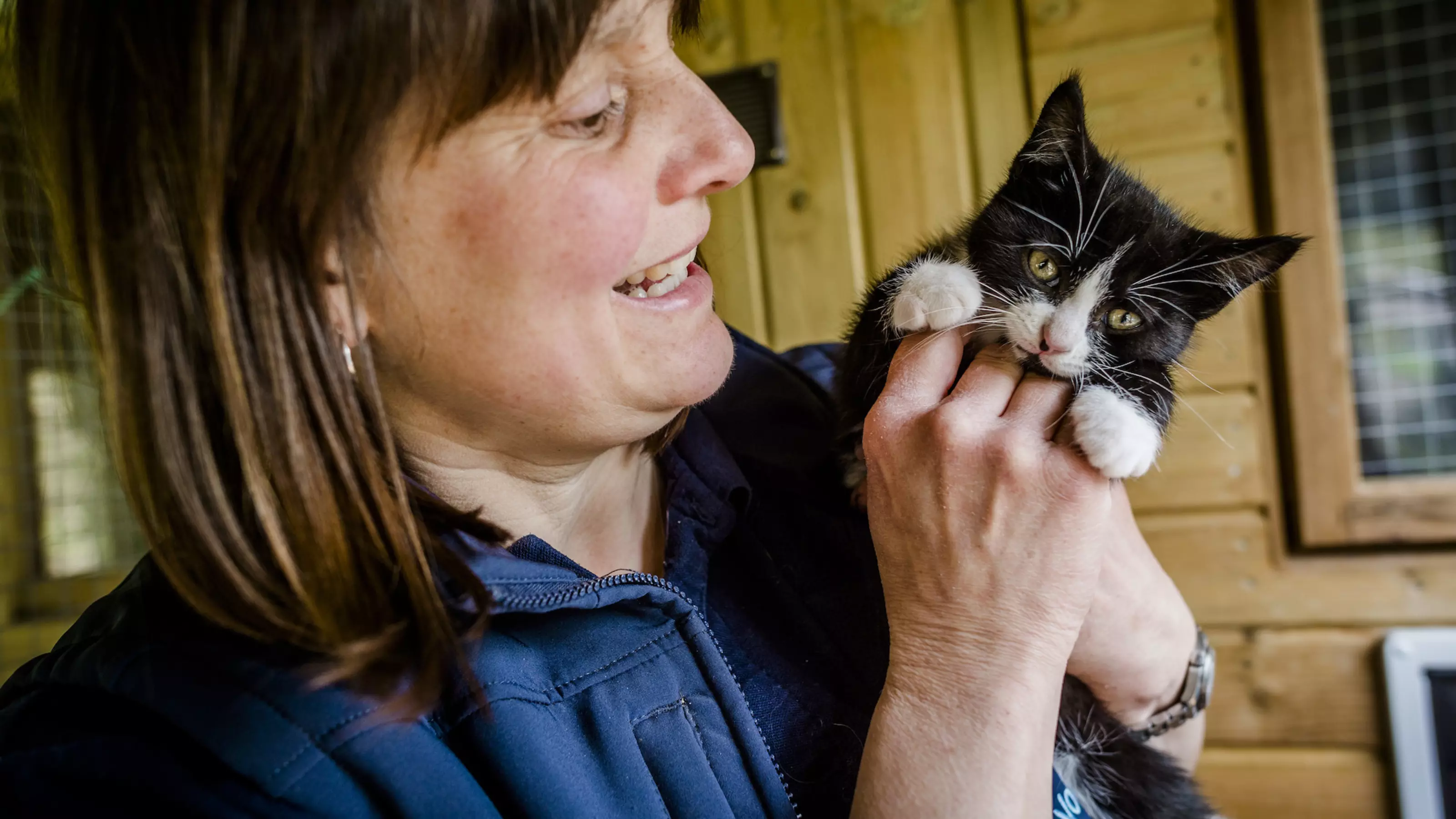 Woman holding black and white kitten